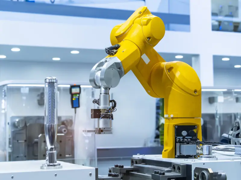 Industrial robotic arm in a factory setting performing automated handling/assembly